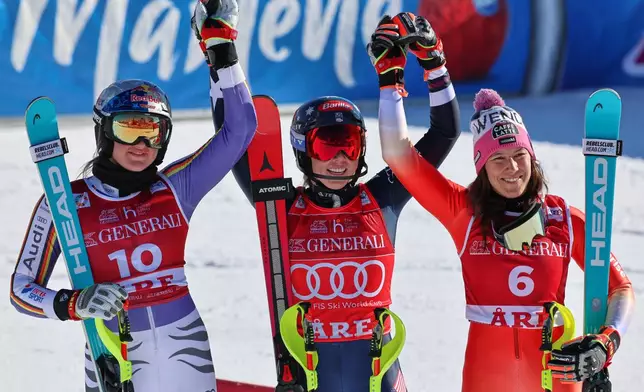 United States' Mikaela Shiffrin, center, winner of an alpine ski, women's World Cup slalom, poses with second placed Germany's Emma Aicher, left, and third placed Switzerland's Wendy Holdener, in Are, Sweden, Sunday, March 15, 2026. (AP Photo/Marco Trovati)