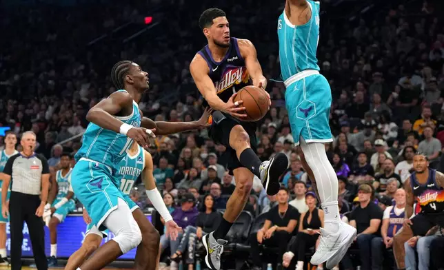 Phoenix Suns guard Devin Booker drives between Charlotte Hornets forward Moussa Diabate, guard Josh Green (10) and forward Miles Bridges during the first half of an NBA basketball game, Sunday, March 8, 2026, in Phoenix. (AP Photo/Rick Scuteri)