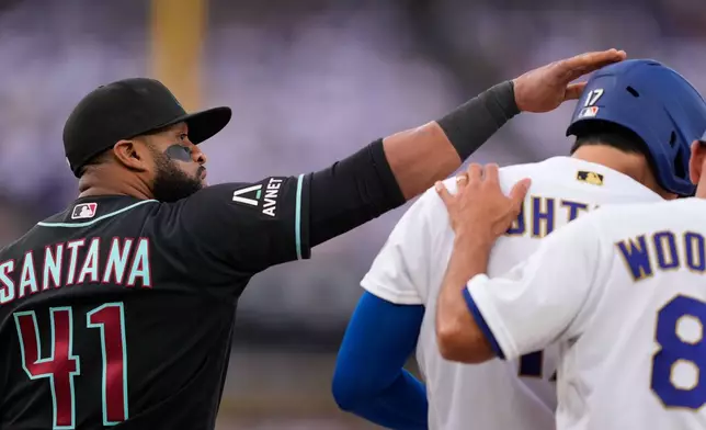 Arizona Diamondbacks first baseman Carlos Santana, left, pats Los Angeles Dodgers' Shohei Ohtani on the head after Ohtani walked during the first inning of a baseball game Saturday, March 28, 2026, in Los Angeles. (AP Photo/Mark J. Terrill)