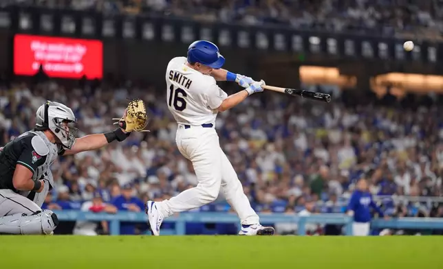Los Angeles Dodgers' Will Smith, right, hits a two-run home run as Arizona Diamondbacks catcher James McCann watches during the eighth inning of a baseball game Saturday, March 28, 2026, in Los Angeles. (AP Photo/Mark J. Terrill)