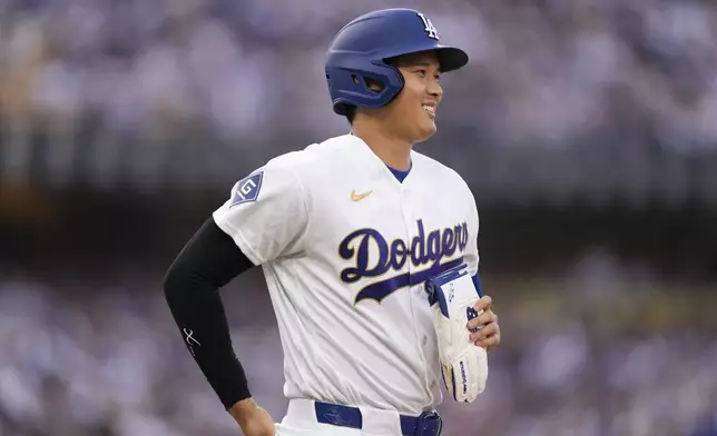 Los Angeles Dodgers' Shohei Ohtani smiles as he heads to first after walking during the first inning of a baseball game against the Arizona Diamondbacks, Saturday, March 28, 2026, in Los Angeles. (AP Photo/Mark J. Terrill)