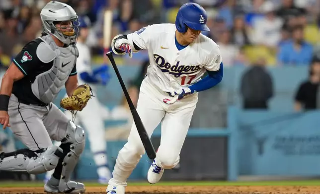 Los Angeles Dodgers' Shohei Ohtani, right, drops his bat as he hits into a double play as Arizona Diamondbacks catcher James McCann watches during the fifth inning of a baseball game Saturday, March 28, 2026, in Los Angeles. (AP Photo/Mark J. Terrill)