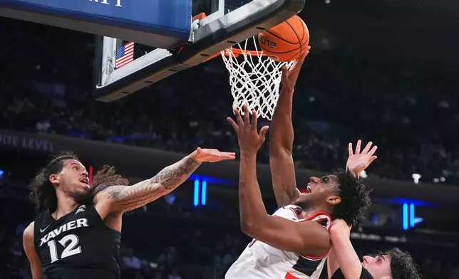 UConn's Tarris Reed Jr., center, shoots over Xavier's Tre Carroll, left, and Jovan Milicevic during first half of an NCAA college basketball game in the quarterfinals of the Big East basketball tournament Thursday, March 12, 2026, in New York. (AP Photo/Frank Franklin II)