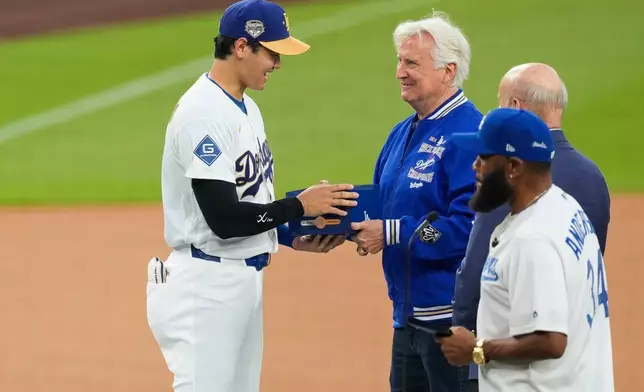 Los Angeles Dodgers Shohei Ohtani receives his ring from Los Angeles Dodgers owner Mark Walter during a World Series Champion ring ceremony prior to a baseball game against the Arizona Diamondbacks in Los Angeles, Friday, March 27, 2026. (AP Photo/Caroline Brehman)
