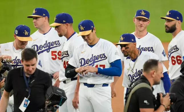 Los Angeles Dodgers Shohei Ohtani adjusts his ring during a World Series Champion ring ceremony prior to a baseball game against the Arizona Diamondbacks in Los Angeles, Friday, March 27, 2026. (AP Photo/Caroline Brehman)