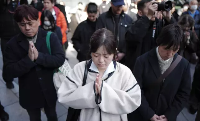 Bystanders pray at 2:46 p.m., Wednesday, March 11, 2026 in Tokyo, as Japan marked the 15th anniversary of the 2011 earthquake, tsunami, and nuclear disaster that devastated the northeastern coast. (AP Photo/Eugene Hoshiko)