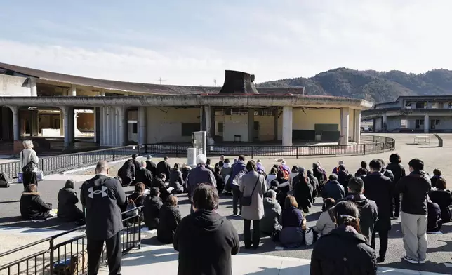 Peopel mourn in front of former Okawa Elementary School where lots of children and teachers from the school lost their lives by the massive tsunami in Ishinomaki, Miyagi Prefecture, northern Japan Wednesday, March 11, 2026, as the country marked the 15th anniversary of the massive earquake, tsunami and nuclear disaster. (Mizuki Sakai/Kyodo News via AP)