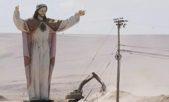 A statue of "Cristo de la Paz" stands on the border crossing between Chile and Peru, as an excavator digs up dirt in order to install barriers to deter irregular migration, in Chacalluta, Arica province, Chile, Tuesday, March 17, 2026. (AP Photo/Esteban Felix)
