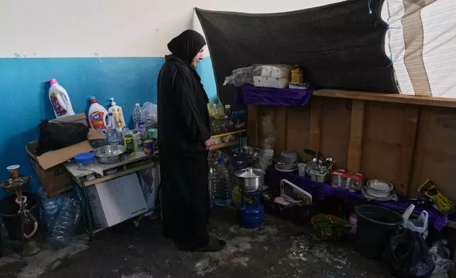 A displaced woman who fled Israeli airstrikes with her family in southern Lebanon cooks food at a school being used as a shelter in Beirut, Lebanon, Tuesday, March 17, 2026. (AP Photo/Bilal Hussein)