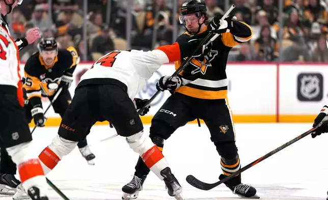 Pittsburgh Penguins' Rickard Rakell, center right, and Philadelphia Flyers' Sean Couturier, center left, face-off during the second period of an NHL hockey game in Pittsburgh, Saturday, March 7, 2026. (AP Photo/Gene J. Puskar)