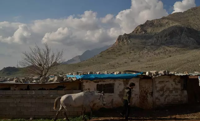 Ako Abdul Rahman, 22, right, an Iraq-Iran cross-border smuggler, leads a horse at a compound in a village in the mountainous Kurdish region near Halabja, Iraq, Tuesday, March 17, 2026. (AP Photo/Leo Correa)