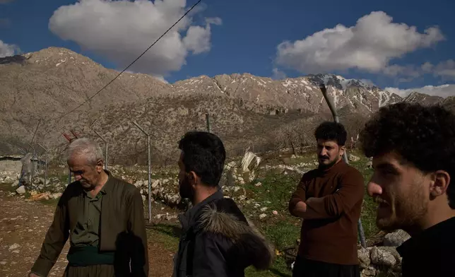 Ako Abdul Rahman, 22, right, an Iraq-Iran cross-border smuggler, chats with local colleagues at a compound in a village in the mountainous Kurdish region near Halabja, Iraq, Tuesday, March 17, 2026. (AP Photo/Leo Correa)