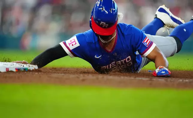 Puerto Rico's MJ Melendez dives back to first during the seventh inning of a World Baseball Classic quarterfinal game against Italy, Saturday, March 14, 2026, in Houston. (AP Photo/Karen Warren)