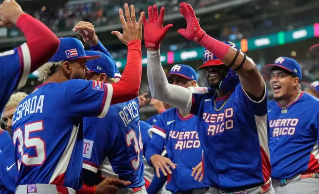 Puerto Rico's Willi Castro, right, is congratulated by teammates after hitting a solo home run during the first inning of a World Baseball Classic quarterfinal game against Italy, Saturday, March 14, 2026, in Houston. (AP Photo/Karen Warren)