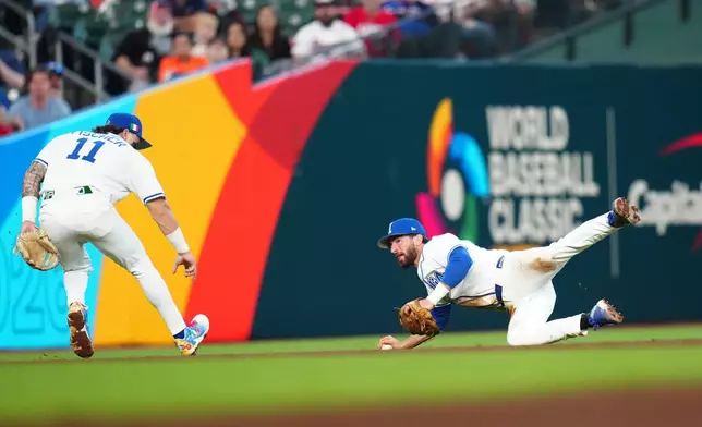 Italy shortstop Thomas Saggese, right, stops a grounder hit for a single by Puerto Rico's Nolan Arenado as Italy's Andrew Fischer (11) watches during the fifth inning of a World Baseball Classic quarterfinal game, Saturday, March 14, 2026, in Houston. (AP Photo/Karen Warren)