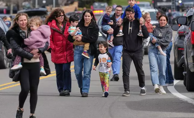 Law enforcement escort families with children away from the Temple Israel synagogue Thursday, March 12, 2026, in West Bloomfield Township, Mich. (AP Photo/Paul Sancya)