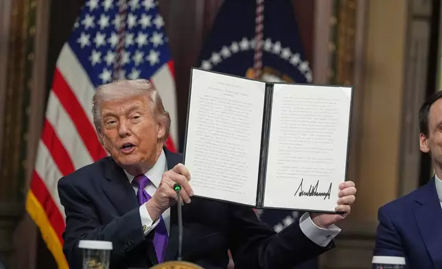 President Donald Trump holds up the Ratepayer Protection Pledge after signing it in the Indian Treaty Room of the Eisenhower Executive Office Building on the White House complex, Wednesday, March 4, 2026, in Washington. (AP Photo/Jacquelyn Martin)