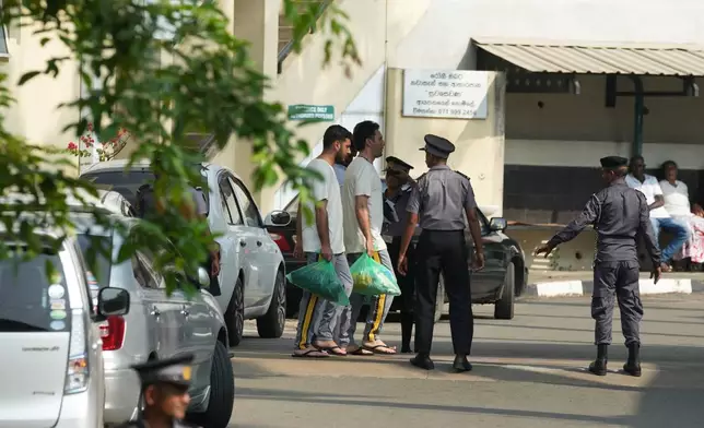 Two Iranian sailors, carrying green bags, who were rescued from IRIS Dena warship by Sri Lanka's navy are escorted to a Judicial Medical Officer from the National Hospital, in Galle, Sri Lanka, Thursday, March 5, 2026. (AP Photo/Eranga Jayawardena)