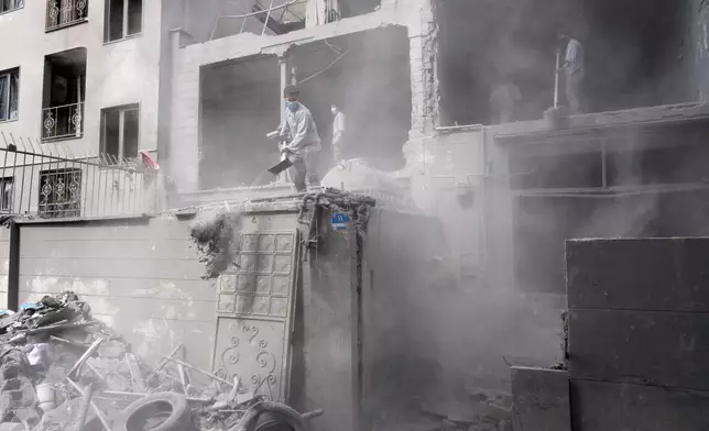 Volunteers clean debris from a residential building damaged when a nearby police station was hit Friday in a U.S.-Israeli strike in Tehran, Iran, Sunday, March 15, 2026. (AP Photo/Vahid Salemi)