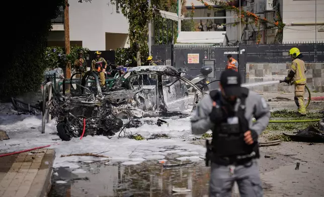 Firefighters extinguish fire at a site damaged during an Iranian missile strike in Tel Aviv, Israel, Sunday, March 15, 2026. (AP Photo/Ohad Zwigenberg)