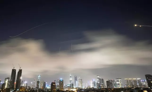 Israeli air defense system fires to intercept missiles during an Iranian attack over Tel Aviv, Israel, early Sunday, March 15, 2026. (AP Photo/Ohad Zwigenberg)