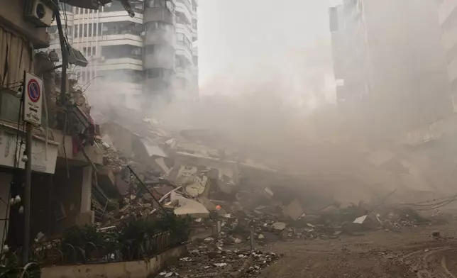 Smoke rises from the rubble of buildings destroyed in an Israeli airstrike in Dahiyeh, Beirut's southern suburbs, Lebanon, Sunday, March 15, 2026. (AP Photo/Hassan Ammar)