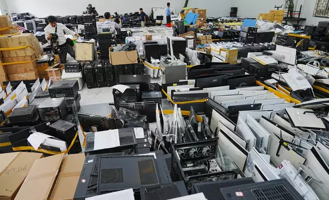 Journalists look at equipment confiscated in a raid by Cambodian police at a scam center in Phnom Penh, Cambodia, Wednesday, March 11, 2026. (AP Photo/Heng Sinith)