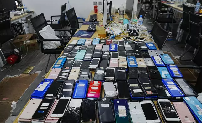 Equipment confiscated in a raid by Cambodian police are laid out on a table at a scam center in Phnom Penh, Cambodia, Wednesday, March 11, 2026. (AP Photo/Heng Sinith)