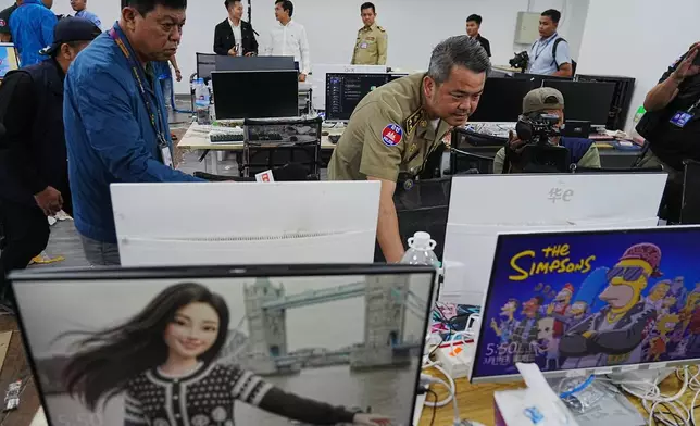 Bun Sosekha, Deputy Commissioner in charge of Security Unit, Phnom Penh Municipal Police, checks equipment confiscated in a raid by Cambodian police at a scam center in Phnom Penh, Cambodia, Wednesday, March 11, 2026. (AP Photo/Heng Sinith)