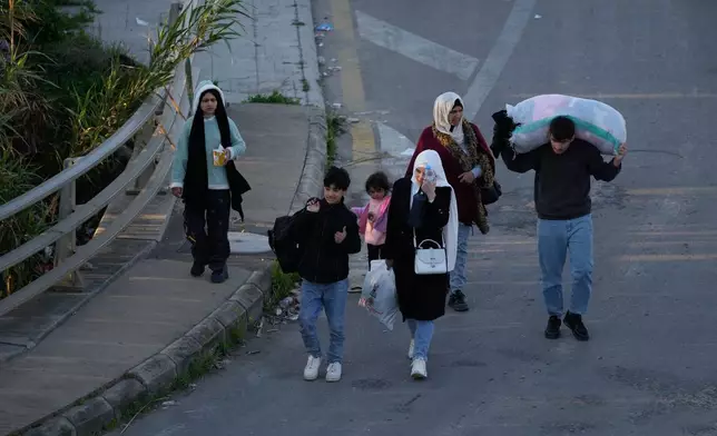 Displaced people carry their belongings fleeing Israeli strikes arrive in southern Lebanon arrive in the southern port city of Sidon, early Monday, March 2, 2026. (AP Photo/Mohammed Zaatari)