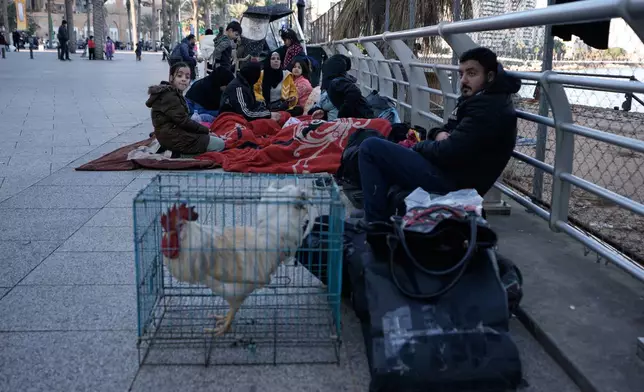 A displaced family fleeing Israeli strikes in Dahiyeh south of Beirut, sits on a sidewalk on Beirut's corniche, Lebanon, Monday, March 2, 2026. (AP Photo/Bilal Hussein)