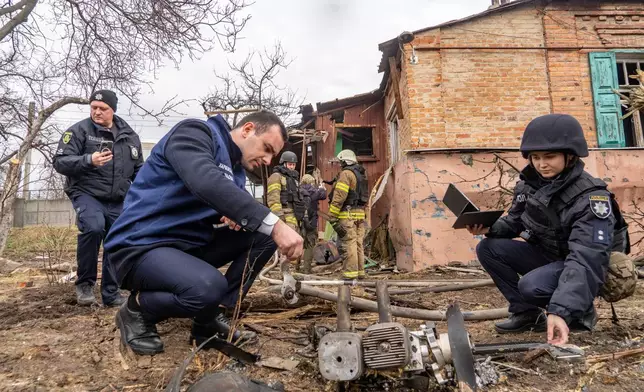 Police officers examine the fragments of a Russian drone that hit a private house during air attack in Kharkiv, Ukraine, Wednesday, March 25, 2026. (AP Photo/Andrii Marienko)