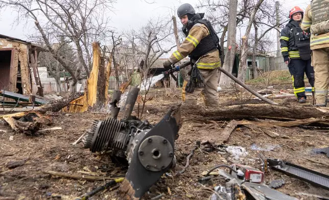 Rescue workers try to put out a fire caused by the fragments of a Russian drone that hit a private house during air attack in Kharkiv, Ukraine, Wednesday, March 25, 2026. (AP Photo/Andrii Marienko)