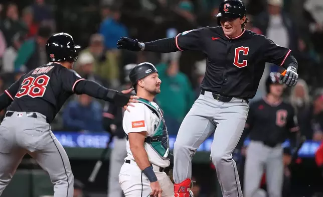 Cleveland Guardians' Chase DeLauter, right, greets Steven Kwan (38) after hitting a two-run home run as Seattle Mariners catcher Cal Raleigh, center, looks away during the 10th inning of a baseball game, Saturday, March 28, 2026, in Seattle. (AP Photo/Lindsey Wasson)