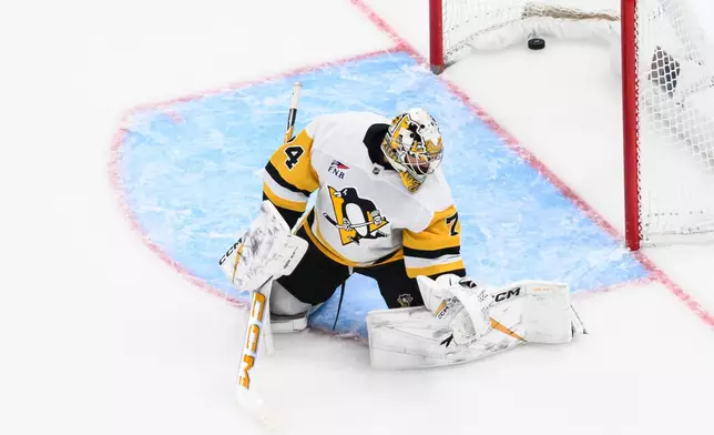 The puck goes past Pittsburgh Penguins goaltender Stuart Skinner (74) from a shot by Utah Mammoth right wing Dylan Guenther during the first period of an NHL hockey game Saturday, March 14, 2026, in Salt Lake City. (AP Photo/Tyler Tate)