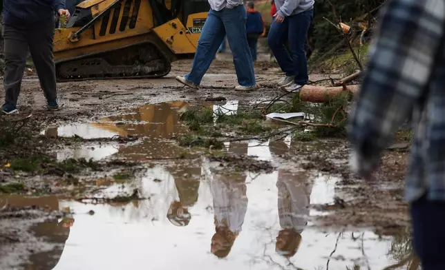 Volunteers are reflected in a puddle of water in the aftermath of a powerful storm that ripped through the area a day earlier, in Union City Mich., Saturday, March 7, 2026. (AP Photo/Nam Y. Huh)