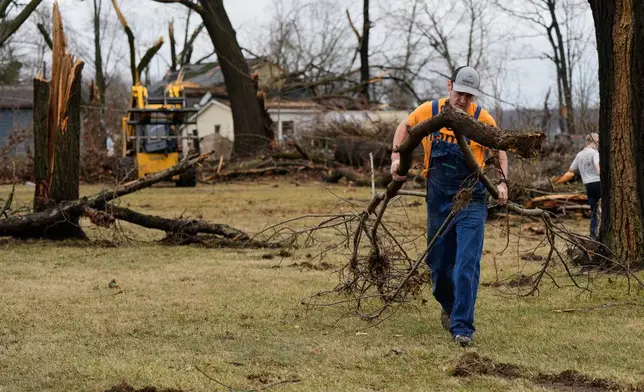 A volunteer clears branches felled by a storm that whipped up a tornado a day earlier, in Union City Mich., Saturday, March 7, 2026. (AP Photo/Nam Y. Huh)