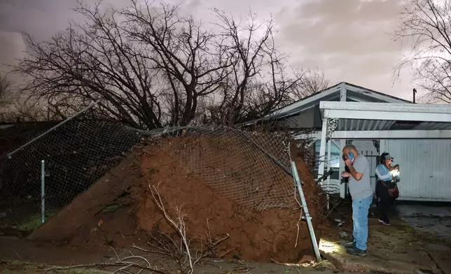 Carlos Lawrence and Miranda Turner view a downed tree from a storm on Friday, March 6, 2026 in Tulsa, Okla. (Mike Simons /Tulsa World via AP)