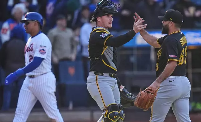 As New York Mets' Juan Soto, left, walks off the field, Pittsburgh Pirates pitcher José Urquidy (65), right, and catcher Henry Davis celebrate after a baseball game, Sunday, March 29, 2026, in New York. (AP Photo/Seth Wenig)