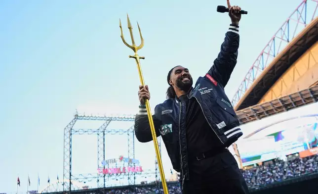 Seattle Seahawks defensive end Leonard Williams holds the trident as he speaks to the crowd before an opening-day baseball game between the Seattle Mariners and the Cleveland Guardians, Thursday, March 26, 2026, in Seattle. (AP Photo/Lindsey Wasson)