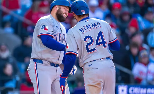 Texas Rangers' Jake Burger, left, celebrates his two-run home run with Brandon Nimmo, right, during the third inning of a baseball game against the Philadelphia Phillies, Saturday, March 28, 2026, in Philadelphia. (AP Photo/Chris Szagola)