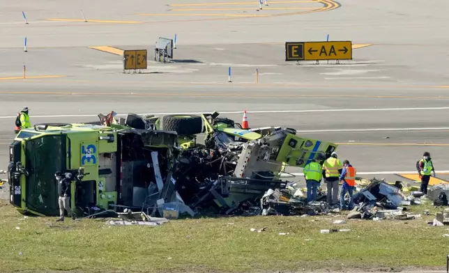 Officials inspect the wreckage of a Port Authority fire truck, Tuesday, March 24, 2026, just off the runway where it had collided with an Air Canada Express jet, Sunday night at LaGuardia Airport in New York. (AP Photo/Yuki Iwamura)