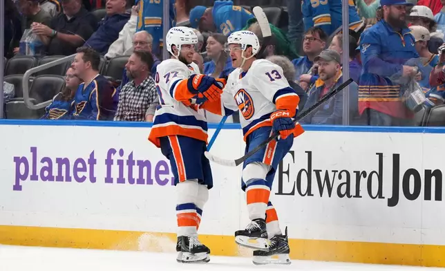 New York Islanders' Mathew Barzal (13) celebrates after scoring during overtime of an NHL hockey game to defeat the St. Louis Blues as teammate Tony DeAngelo (77) looks on Tuesday, March 10, 2026, in St. Louis. (AP Photo/Jeff Roberson)