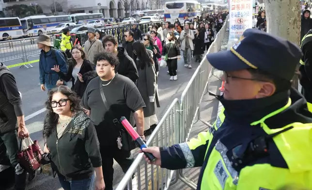 A South Korean police officer signals to pedestrians near the venue of the comeback concert of K-pop band BTS in Seoul, South Korea, Saturday, March 21, 2026. (AP Photo/Lee Jin-man)