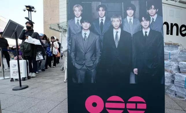 People wait to receive special edition of local news papers reporting the comeback of K-pop band BTS near Gwanghwamun Square in Seoul, South Korea, Saturday, March 21, 2026. (AP Photo/Ahn Young-joon)