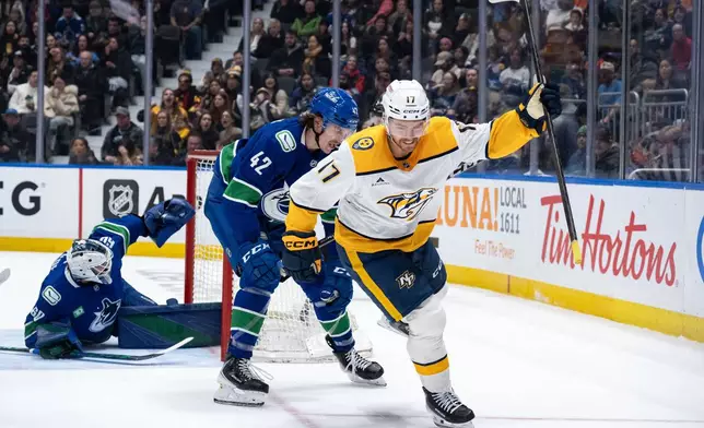 Nashville Predators' Tyson Jost (17) celebrates his goal as Vancouver Canucks' Curtis Douglas (42) watches and goaltender Nikita Tolopilo (60) looks to the net during the first period of an NHL game in Vancouver, on Thursday, March 12, 2026. (Ethan Cairns/The Canadian Press via AP)