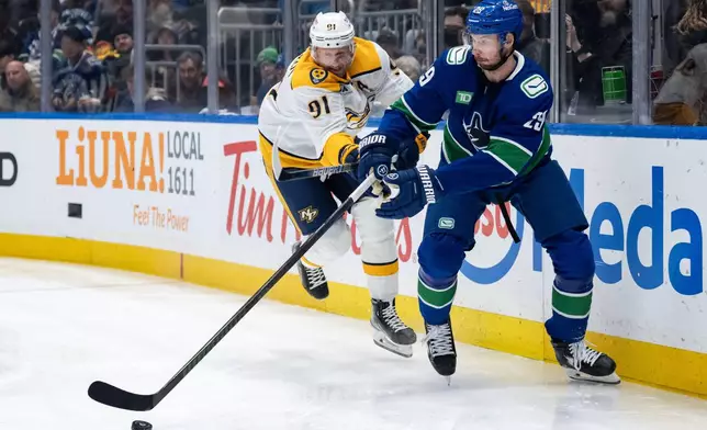 Nashville Predators' Steven Stamkos (91) and Vancouver Canucks' Marcus Pettersson (29) vie for the puck during the first period of an NHL game in Vancouver, on Thursday, March 12, 2026. (Ethan Cairns/The Canadian Press via AP)