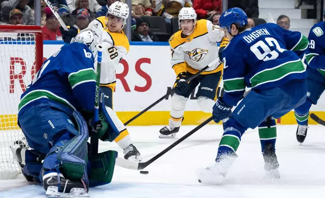 Nashville Predators' Zachary L'heureux (68) and Luke Evangelista (77) watch as Vancouver Canucks' Liam Ohgren (92) tips in the puck from Nashville's Matthew Wood, not seen, past Vancouver goaltender Nikita Tolopilo (60) during the second period of an NHL game in Vancouver, on Thursday, March 12, 2026. (Ethan Cairns/The Canadian Press via AP)