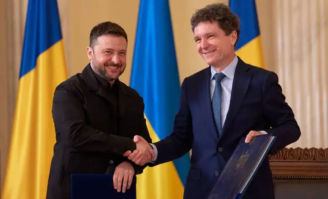 Ukrainian President Volodymyr Zelenskyy, left, shakes hands with Romanian President Nicusor Dan holding bilateral cooperation documents after a signing ceremony at the Cotroceni Presidential Palace in Bucharest, Romania, Thursday, March 12, 2026. (AP Photo/Andreea Alexandru)