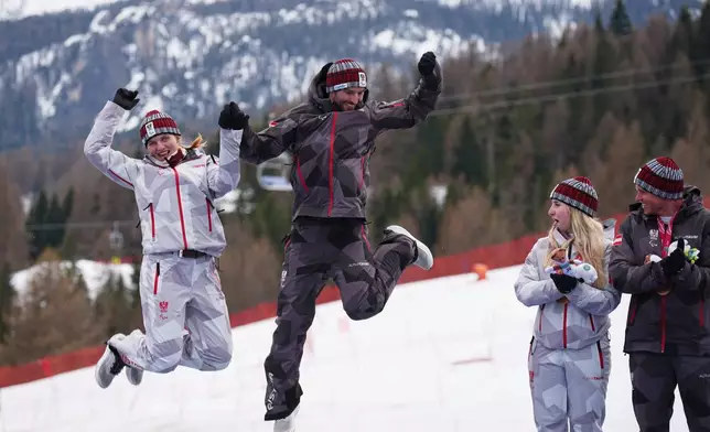 Gold medalists Veronika Aigner, of Austria, left, and her guide Eric Digruber celebrate on the podium of the alpine skiing women's giant slalom vision impaired, watched by bronze medalists Elina Stary, of Austria, and her guide Stefan Winter, right, at the 2026 Winter Paralympics, in Cortina d'Ampezzo, Italy, Thursday, March 12, 2026. (AP Photo/Emilio Morenatti)